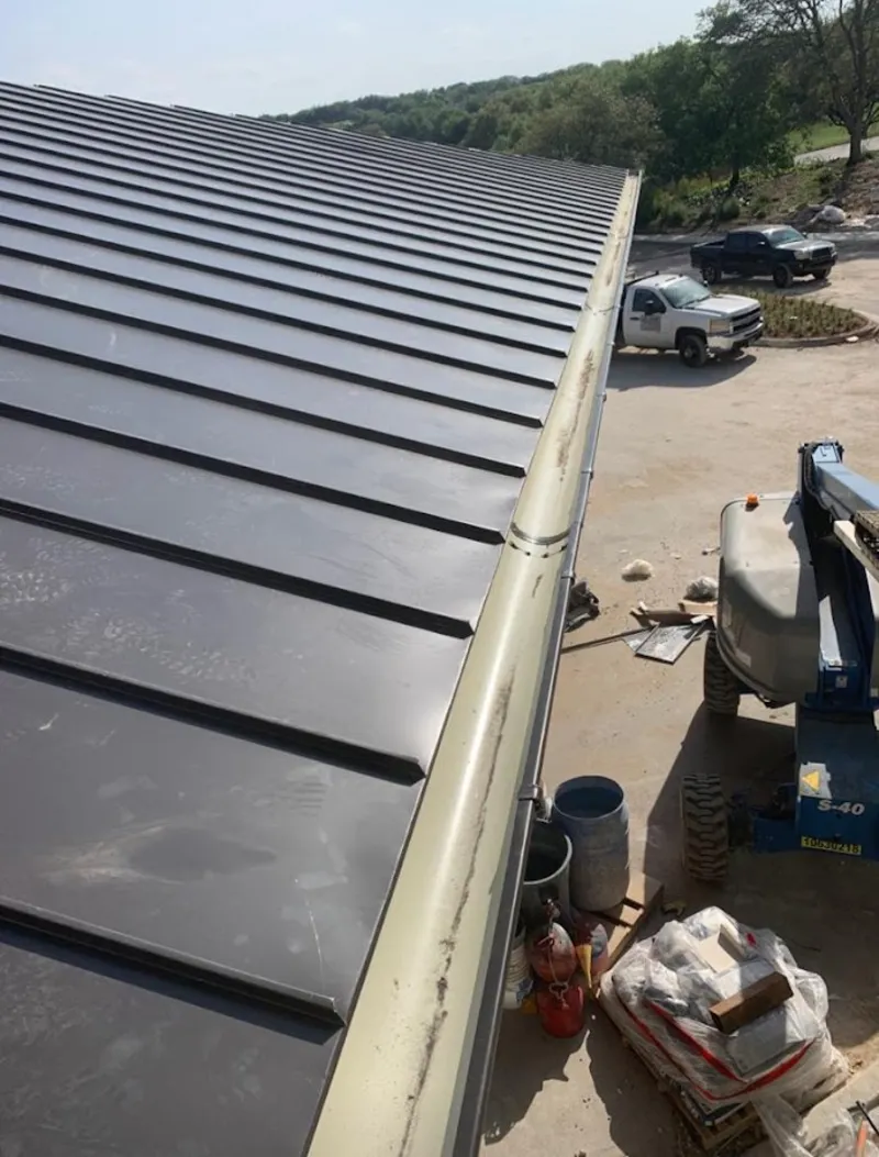 Standing seam panel and gutter detail on a metal roofing jobsite in Byram